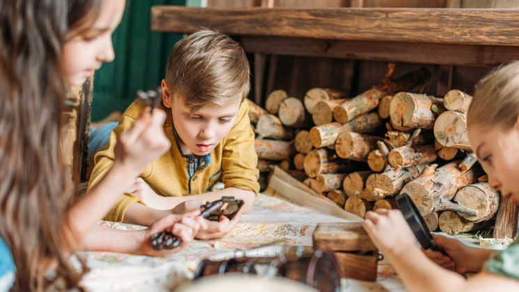 kids looking at map next to logs.