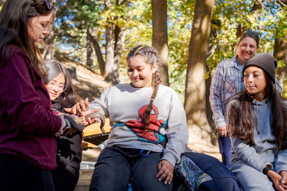 Students and an instructor gathered for an outdoor lesson in the forest at Pali Institute