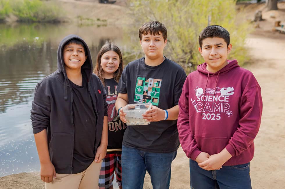 A group of students holding a specimen container beside the lake at Pali Institute